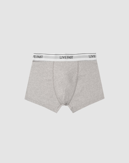 LIVE FAST DIE YOUNGs Live Fast Trunks (2 Pack) feature gray mens boxer briefs in soft cotton with a LIVE FAST black elastic waistband. Care instructions for easy maintenance included; shown on a light gray background.