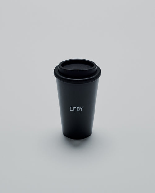 The LFDY Coffee Cup by LIVE FAST DIE YOUNG is a black double-walled to-go cup with a black plastic screw cap and LFDY in white on the front, shown against a plain light gray background.