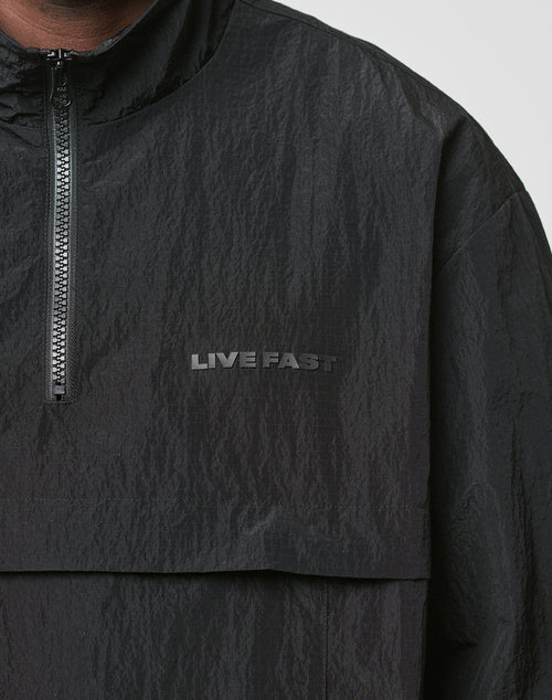 A close-up of the LIVE FAST DIE YOUNG Live Fast Nylon Halfzip, a black nylon jacket with a zipper, oversized fit, and LIVE FAST printed in black on the chest.