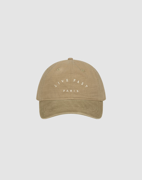The Live Fast Paris Cap by LIVE FAST DIE YOUNG is a beige 100% Baumwolle baseball cap featuring "LIVE FAST" in white above "PARIS" on the front, shown against a plain light gray background.