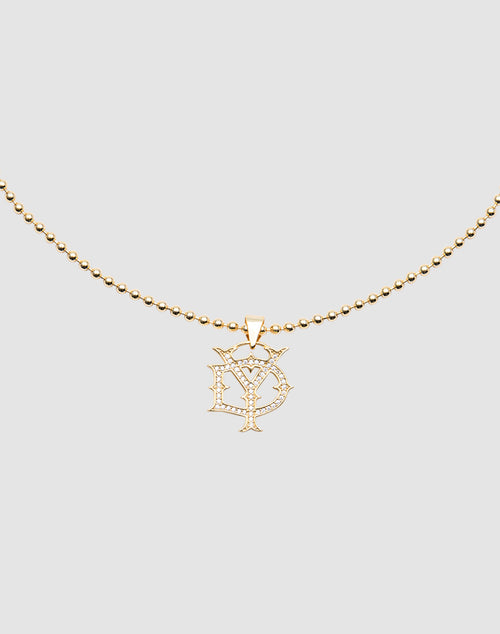 The DY Chain by LIVE FAST DIE YOUNG is a gold-plated beaded necklace with a cubic zirconia pendant featuring stylized overlapping D and Y letters, shown on a plain light gray background.