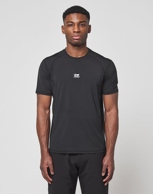 A man faces forward against a white background, wearing the LIVE FAST DIE YOUNG Live Fast Performance Tee in black, featuring a slim fit, short sleeves, small white chest logo, and comfortable Nylon Spandex material with matching black pants.