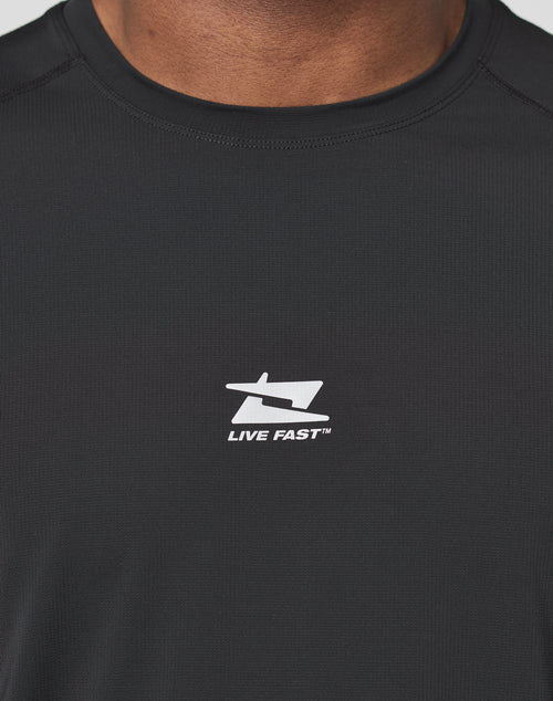 Close-up of a person wearing the LIVE FAST DIE YOUNG Live Fast Performance Tee, a black slim-fit shirt made from comfortable nylon spandex, featuring a white stylized “L” and “F” logo above the text “LIVE FAST™” on the chest.