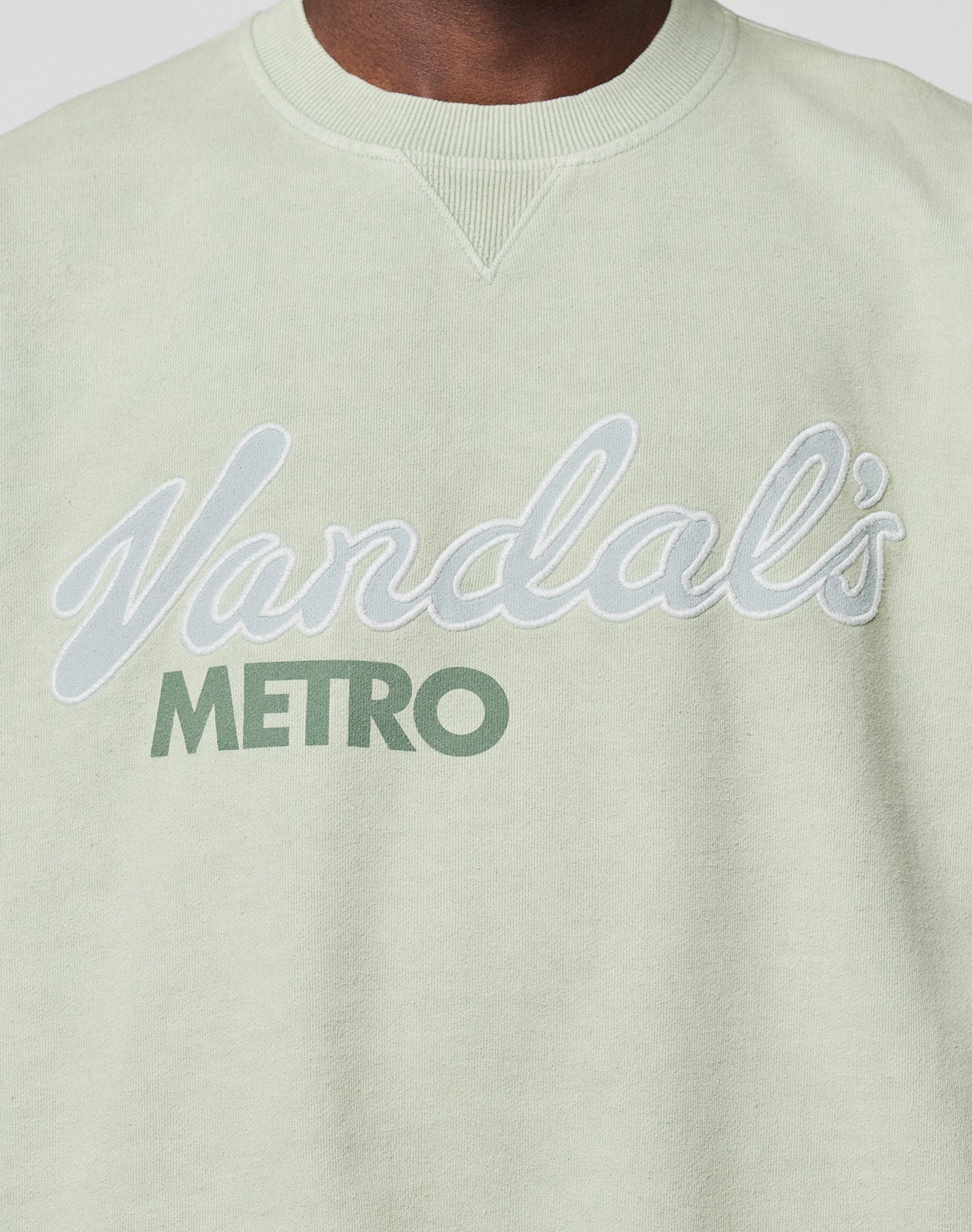 A close-up of the LFDY Vandals Sweater by LIVE FAST DIE YOUNG in light green, featuring an individueller Wasch-Effekt and "Vandals METRO" in white and green lettering. Made from 100% Baumwolle with a relaxed Oversize Fit.