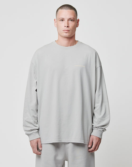 A person with short hair stands against a plain background wearing the LIVE FAST DIE YOUNG Basic Longsleeve and matching pants in light grey, both made from 100% Baumwolle, with a neutral expression and arms by their sides.