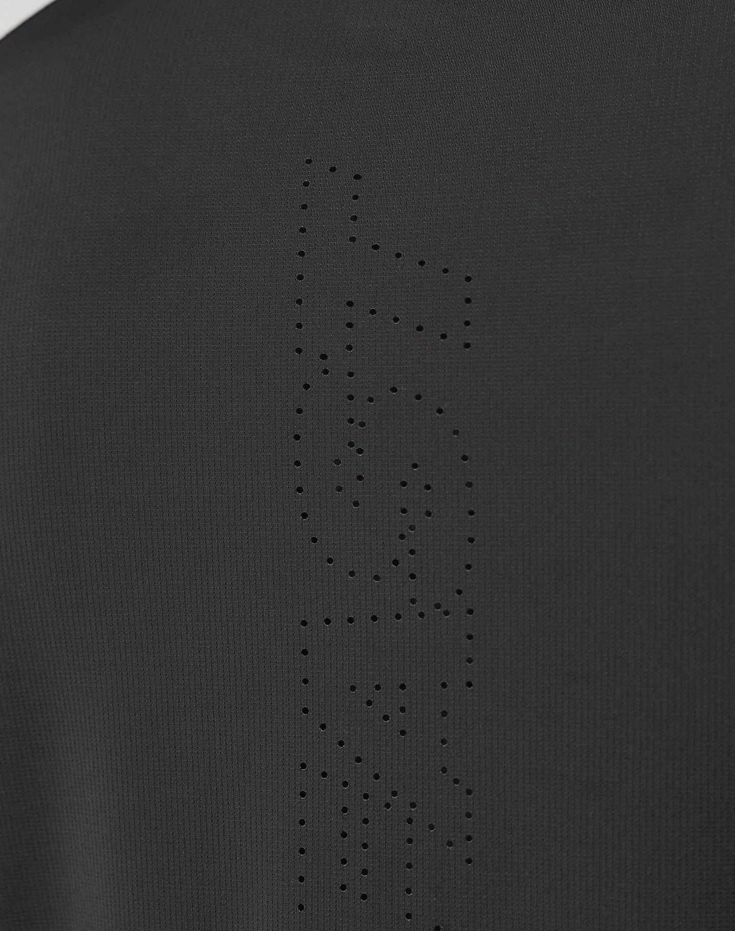 Close-up of the Live Fast Performance Longsleeve by LIVE FAST DIE YOUNG, showing black fabric with a mesh insert and perforated holes forming FAST vertically, highlighting the garment’s texture and fine details.