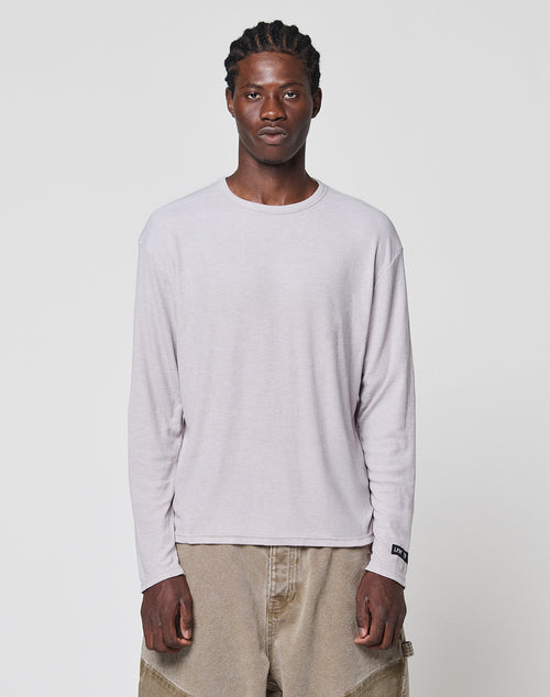 A man with braided hair wears the LIVE FAST DIE YOUNG LFDY Rib Longsleeve and loose tan pants, standing facing forward against a plain white background.