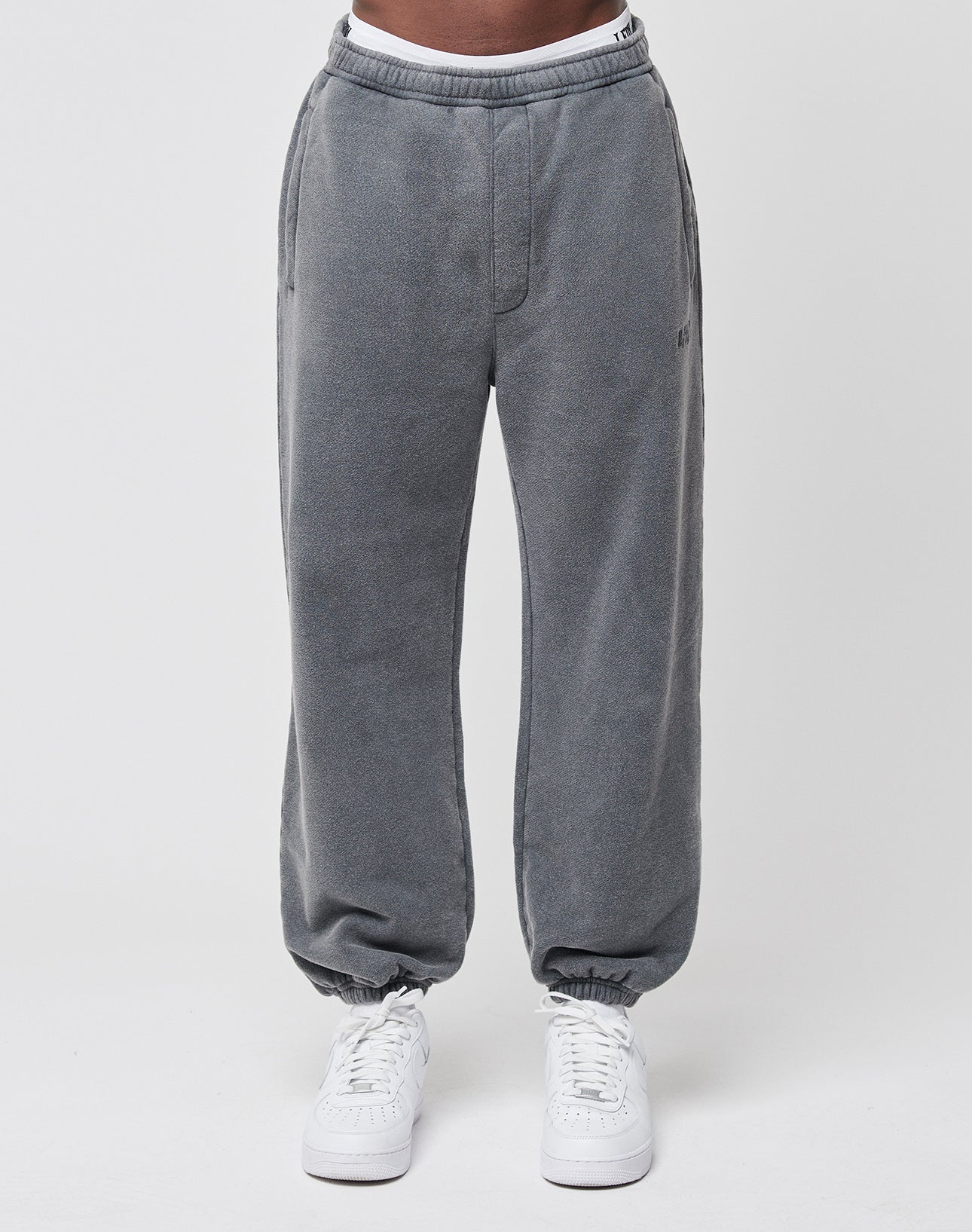 A person wearing gray Loose Jogger sweatpants from LIVE FAST DIE YOUNG with an elastic waistband and white sneakers, standing against a plain white background.