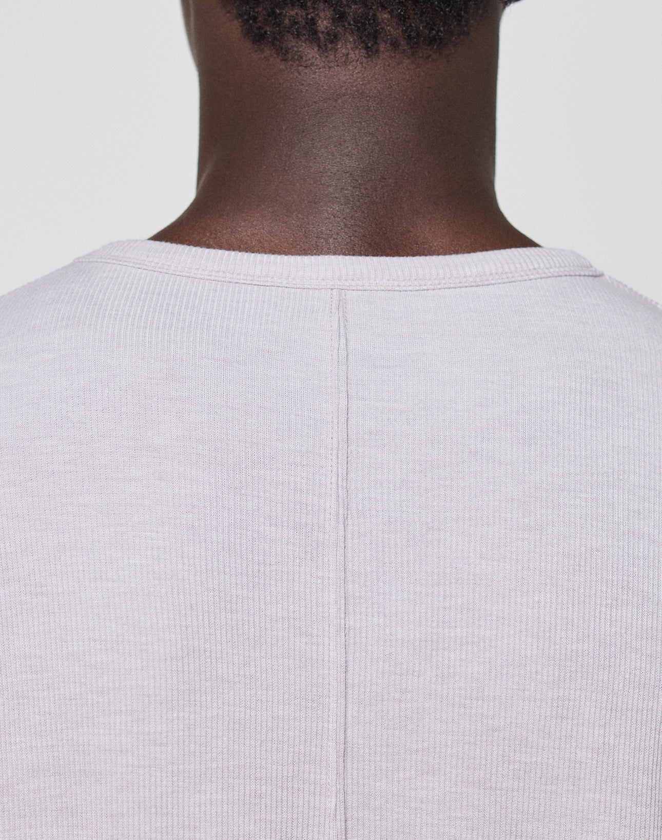 Close-up of the back neck and shoulders wearing the LFDY Rib Longsleeve by LIVE FAST DIE YOUNG—a light beige ribbed shirt featuring a central seam and subtle topstitching, set against a plain light background.