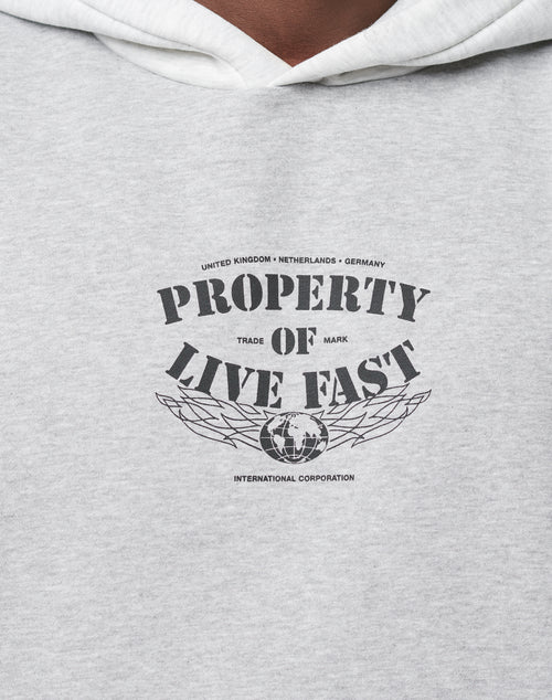 A close-up of the Live Fast Property Hooded by LIVE FAST DIE YOUNG, a gray oversized hoodie with black PROPERTY OF LIVE FAST frontprint, globe graphic, and smaller text: United Kingdom, Netherlands, Germany, International Corporation.