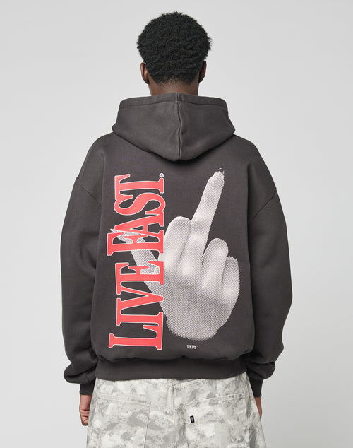 A person faces away from the camera wearing the LFDY Middlefinger Hooded by LIVE FAST DIE YOUNGāan oversize Baumwolle-Polyester hoodie with a bold red āLIVE FASTā and a middle finger hand graphic on the back.