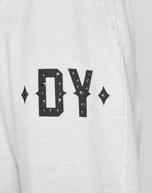 Close-up of DY Rivet Shorts by LIVE FAST DIE YOUNG, in light gray and oversize fit. Features large black DY letters with metallic studs and diamond-shaped accents. Made from 100% Baumwolle, shown against a neutral background.