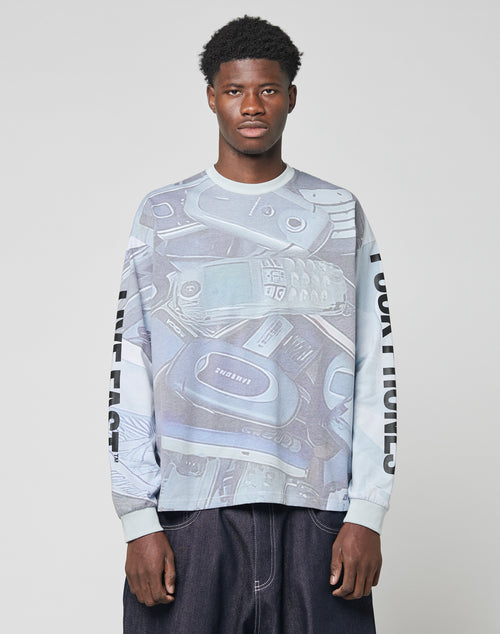 A man stands against a plain backdrop wearing the LFDY Stolen Phones Longsleeve by LIVE FAST DIE YOUNG, an oversize light blue sweatshirt with vintage wash, mobile phones graphic, and LIVE FAST plus FOUR HORNS prints on the sleeve.