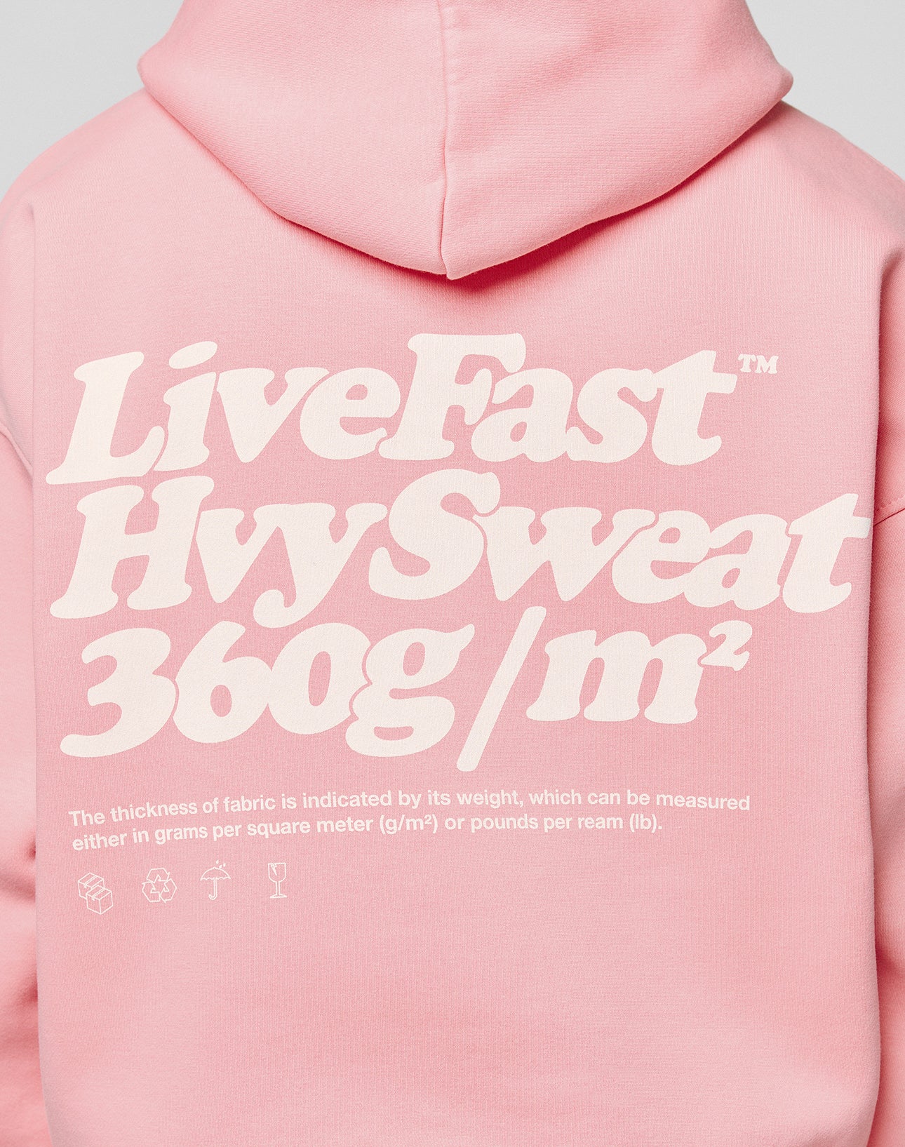 Someone wearing the LIVE FAST DIE YOUNG Basic 360 Hooded in pink—a bold white back print and oversize fit, crafted with heavy 360g/m² fabric (thickness measured by grams per square meter), plus detailed topstitching.