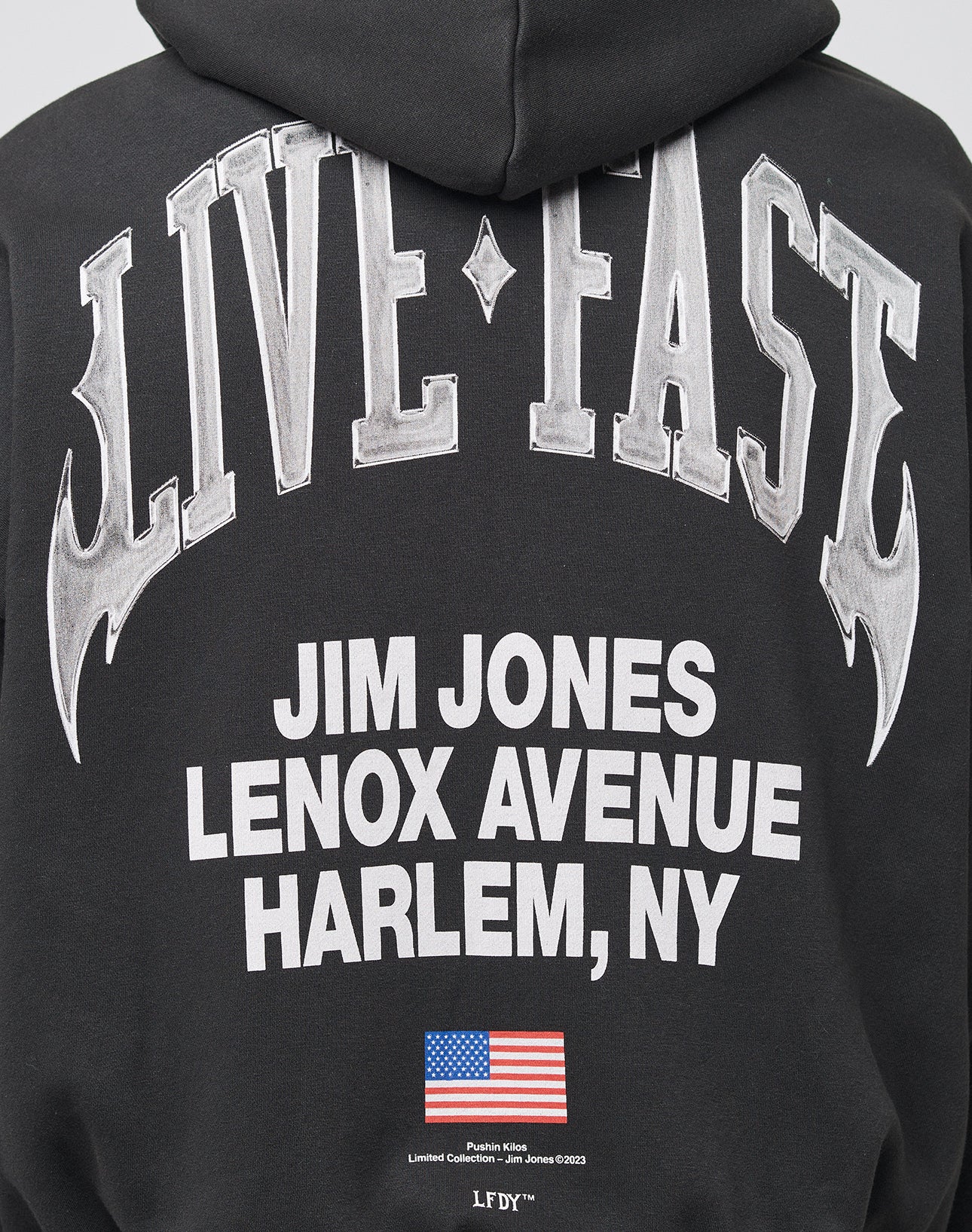 Die LIVE FAST DIE YOUNG Live Fast Lenox Hooded Zip in Oversize-Fit besteht aus Baumwolle und bietet markante Front- und Backprints: LIVE FAST, JIM JONES LENOX AVENUE HARLEM, NY in Weiß, US-Flagge sowie feinem Saumprint.
