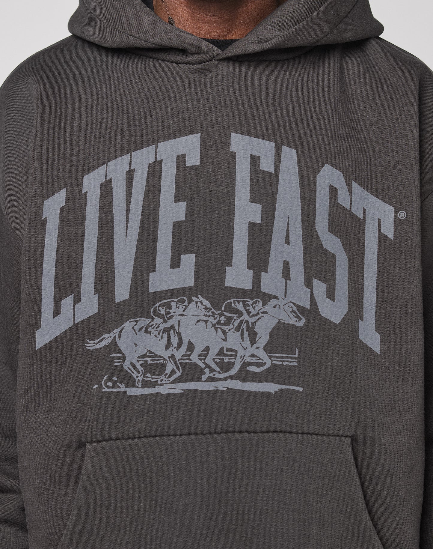 The Live Fast Stallion Hooded by LIVE FAST DIE YOUNG is an oversized charcoal hoodie featuring bold LIVE FAST text above two jockeys on racing horses, crafted from soft Baumwolle cotton.