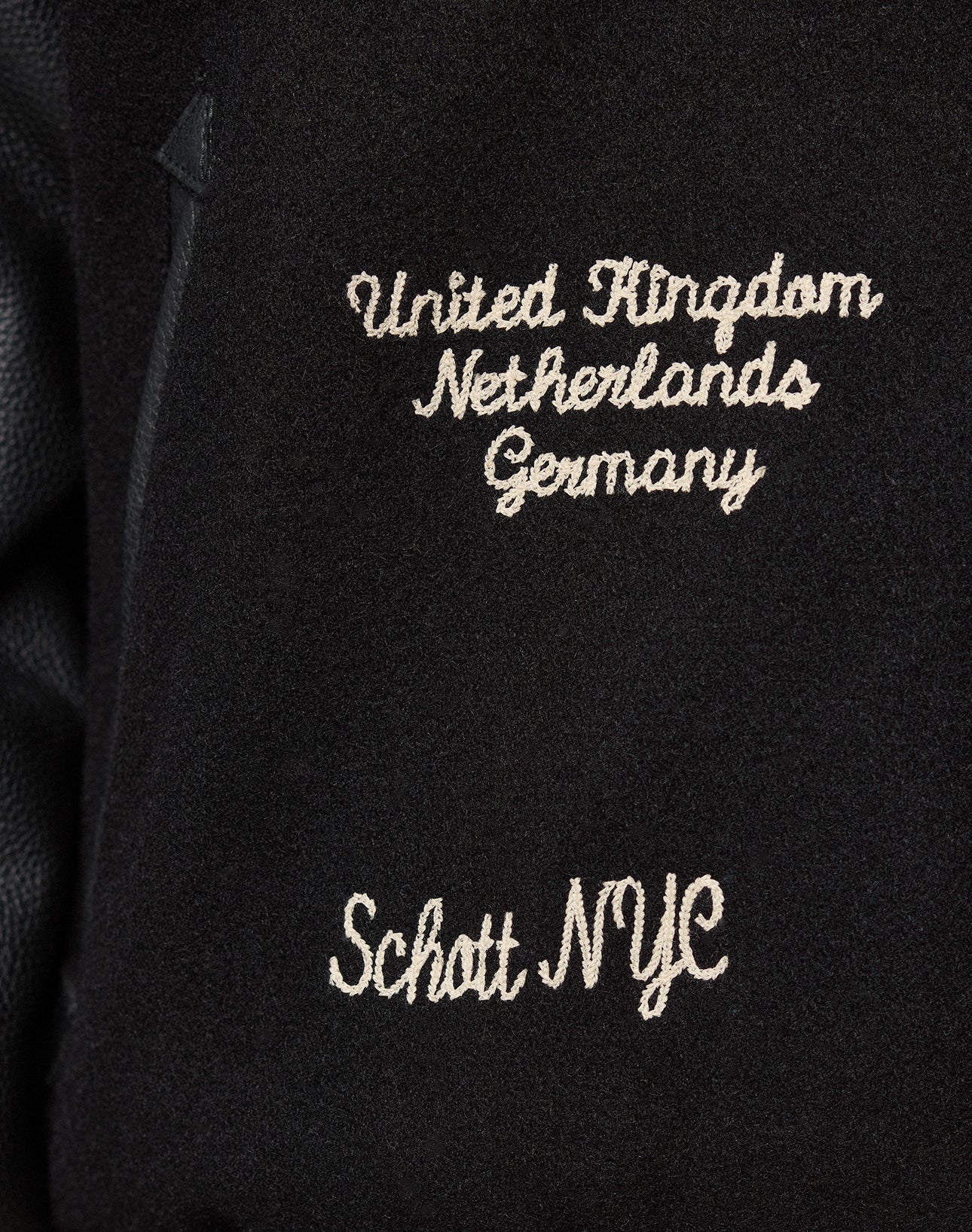 The LFDY x Schott NYC Varsity Jacket by LIVE FAST DIE YOUNG features black fabric with white embroidery of United Kingdom, Netherlands, and Germany above Schott NYC—ideal for a limited edition look.
