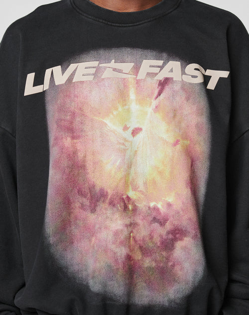 The LFDY Angel Sweater by LIVE FAST DIE YOUNG is a black oversize-fit sweatshirt featuring LIVE FAST in bold above an ethereal angel amid clouds and radiant pink, yellow, and white light, crafted from soft Baumwolle.