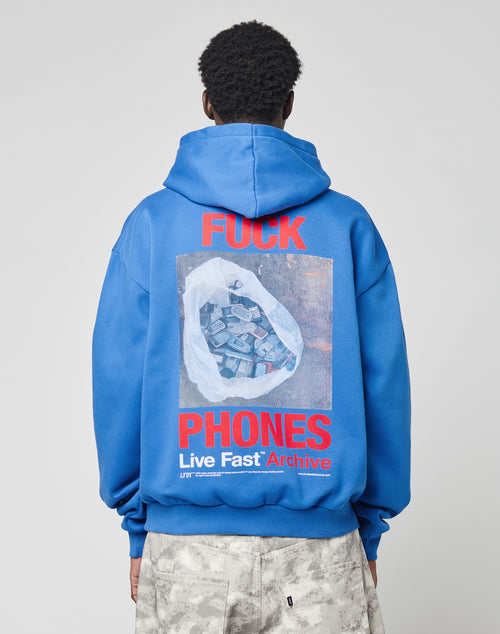 A person faces away in an oversized LFDY F*ck Phones Hoodie by LIVE FAST DIE YOUNG, featuring bold red āFUCK PHONESā text and a graphic of a plastic bag with old phones above āLive Fast Archive,ā crafted from soft cotton.