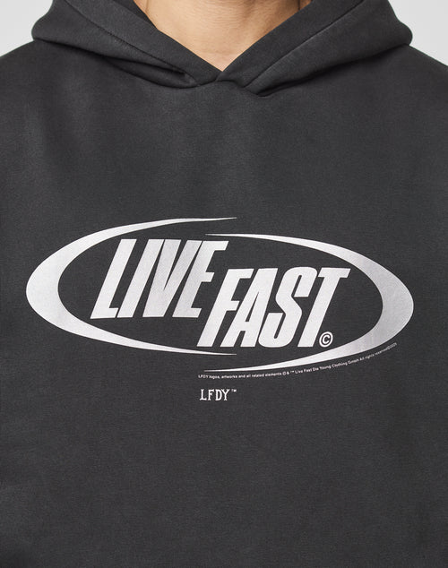 Someone wears the LFDY Sphere Hooded by LIVE FAST DIE YOUNG, an oversize black cotton hoodie with LIVE FAST in bold silver oval front print and LFDY below in smaller text.