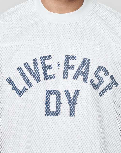A person wears the LFDY Boxy Jersey by LIVE FAST DIE YOUNG, a boxy fit white mesh top with blue polka-dot front print letters. Only the neck and upper chest are visible.