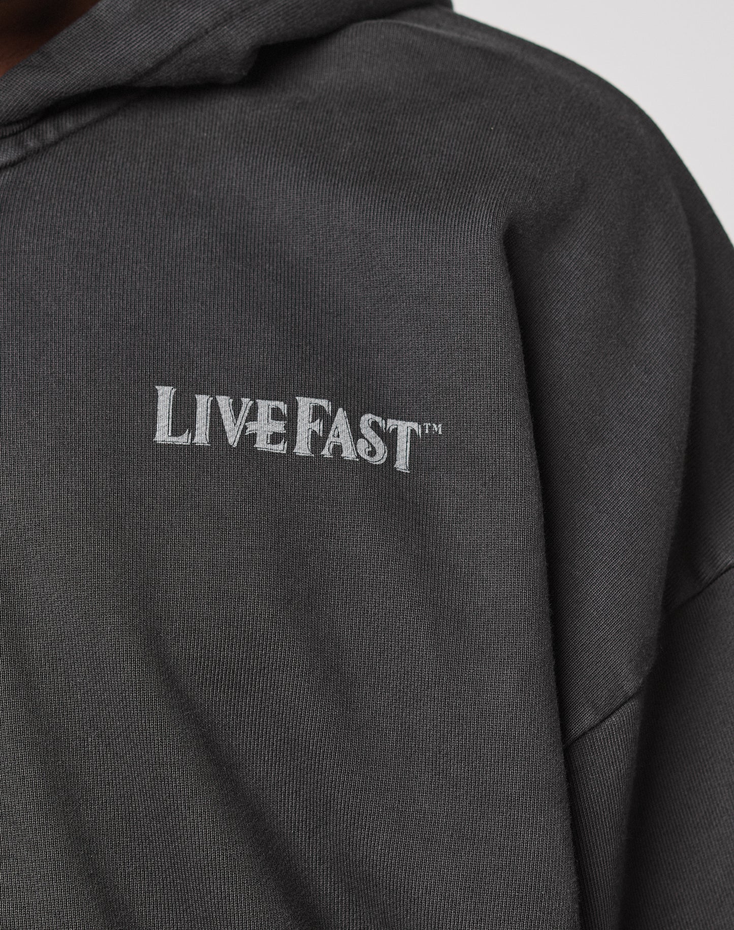 Close-up of the LFDY Loyal Hooded Zip by LIVE FAST DIE YOUNG, a dark hoodie with Vintage Waschung and LIVE FAST™ in white on the chest, made from 100% Baumwolle in an Oversize Fit.