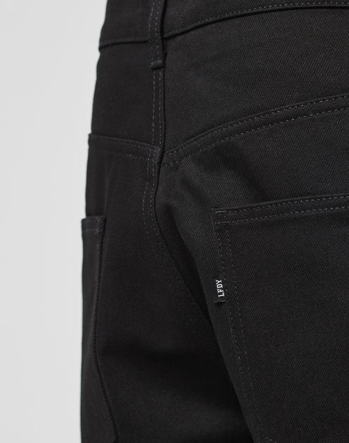 Close-up of the back pocket area of LFDY Baggy Denim in black, featuring visible stitching and a small fabric tag on the seam. Made from 100% Baumwolle for lasting comfort and durability.