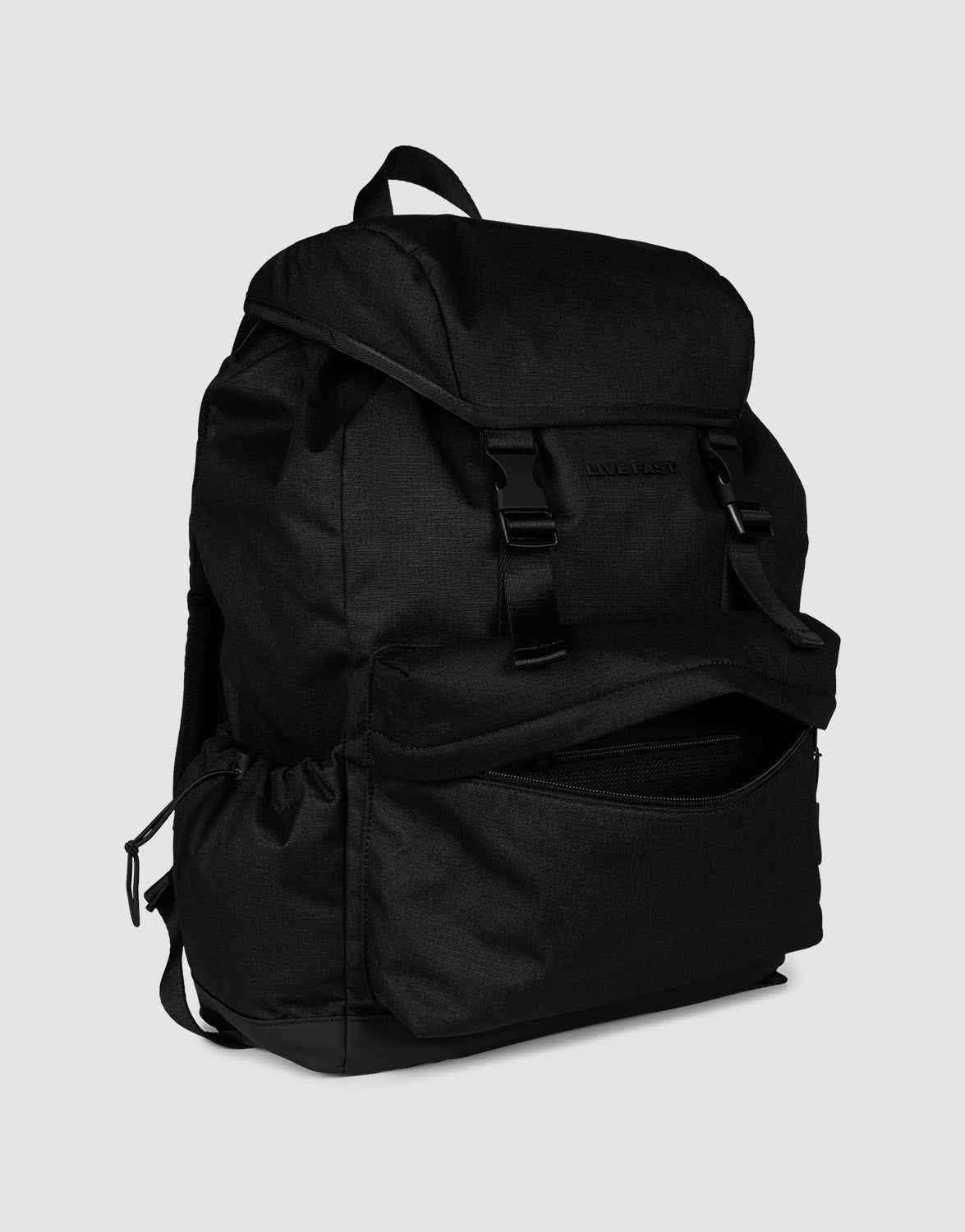 The LIVE FAST DIE YOUNG LFDY Travel Backpack in black features a flap top, two front buckles, a zippered 25L front pocket revealing the interior, and side pockets. It is displayed on a plain light gray background.