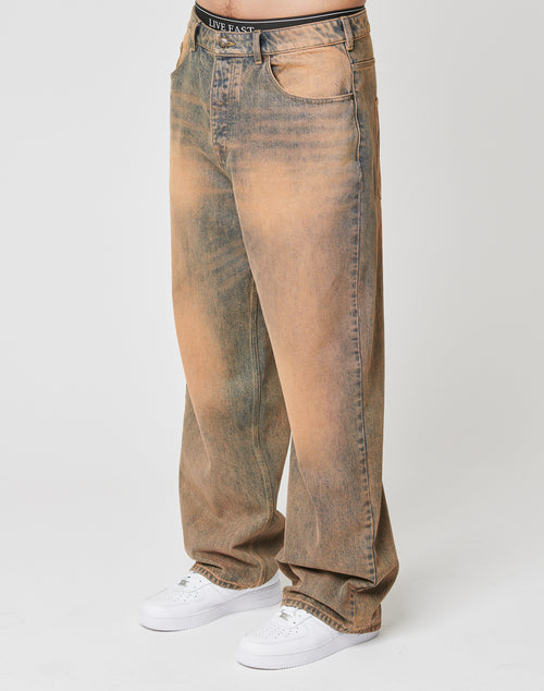 Wearing LFDY Baggy Denim by LIVE FAST DIE YOUNG—loose, high-waisted, faded brown and blue 100% Baumwolle jeans with a weites gerades Bein, baggy fit, and distressed look—paired with white sneakers. Upper body not visible.