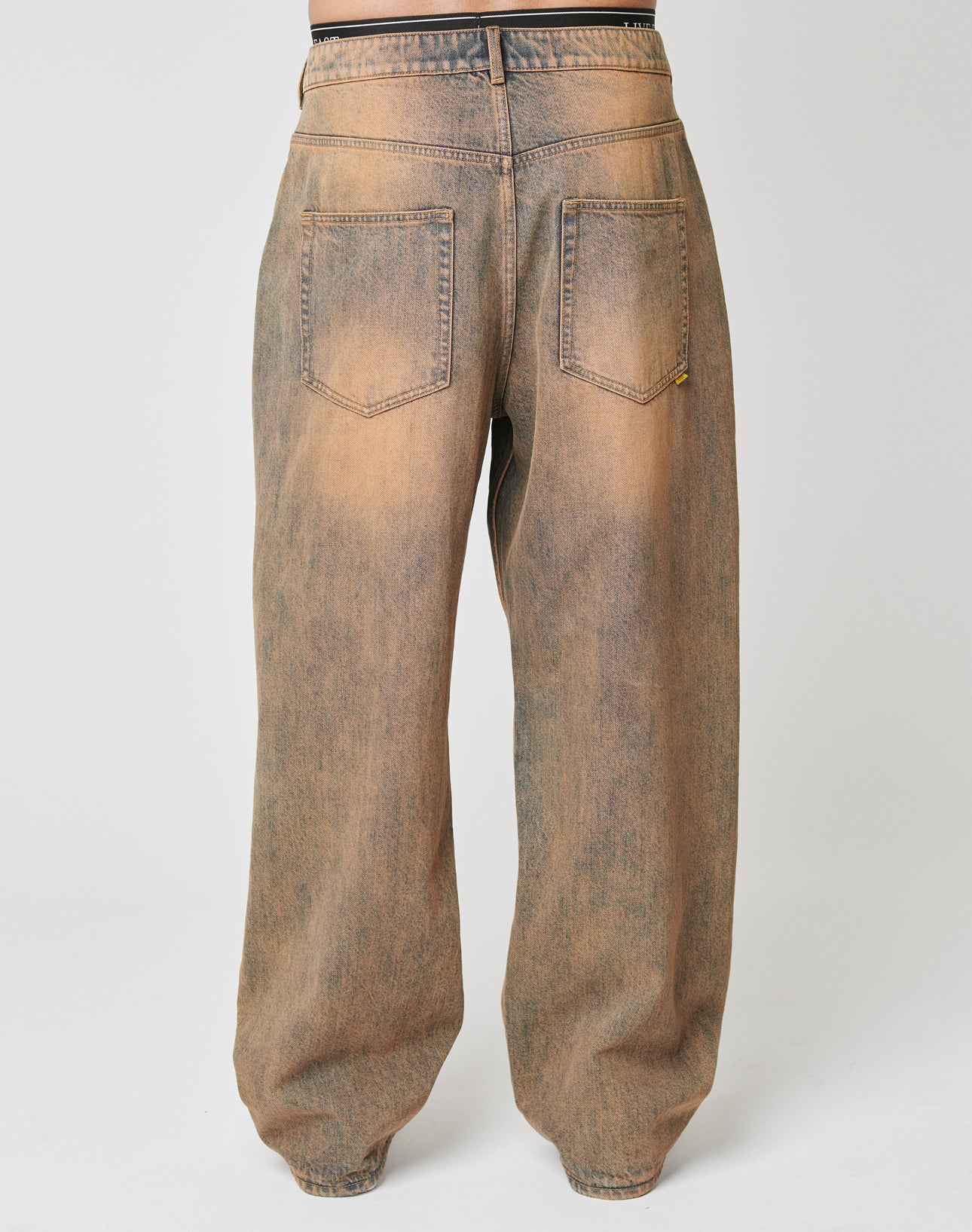 Back view of a person in LIVE FAST DIE YOUNGs LFDY Baggy Denimābrownish-black faded, 100% Baumwolle jeans with two back pockets, a vintage look, and weites gerades Bein that pools at the ankles for relaxed style.