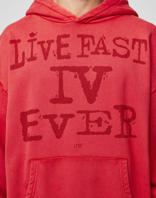 A person wears the LFDY IV Ever Hooded by LIVE FAST DIE YOUNG, an oversized red hoodie with LIVE FAST IV EVER in bold on the front, vintage wash finish, roomy bottom pocket, and made from 100% Baumwolle for comfort.