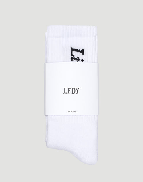 A pair of soft white Live Fast Die Young Socks (2 Pack) by LIVE FAST DIE YOUNG, made from Baumwolle with Polyamid and Elastan, folded together and wrapped in a white band labeled LFDY™ and 2 x Socks, set on a light gray background.