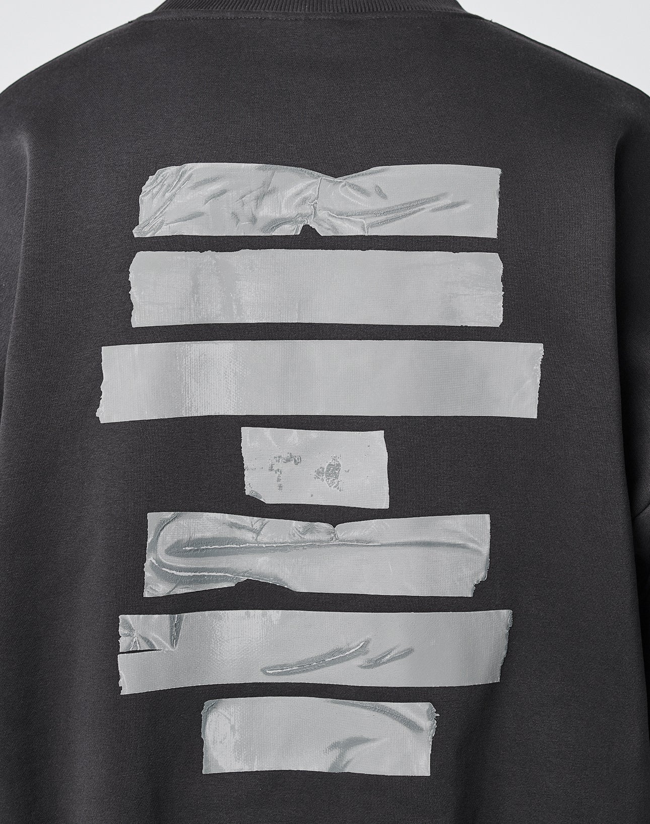 The LIVE FAST DIE YOUNG Tape Sweater is a black oversized sweatshirt with uneven horizontal silver duct tape strips across the back.