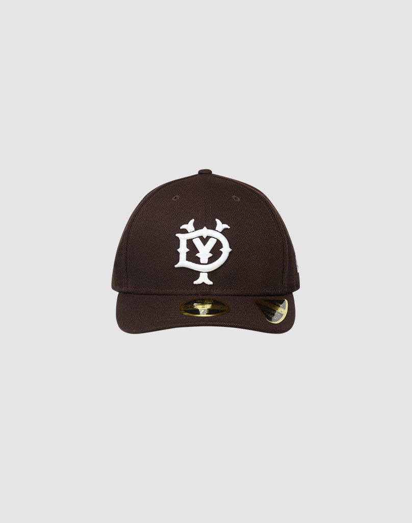 The LFDY X NEW ERA 59FIFTY LOW PROFILE by LIVE FAST DIE YOUNG is a black fitted cap with a white stylized DY logo, low profile silhouette, curved brim with shiny sticker, shown on a plain light gray background.