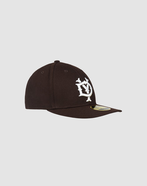 The LFDY X NEW ERA 59FIFTY LOW PROFILE by LIVE FAST DIE YOUNG is a black fitted cap with a flat brim, bold white embroidered front logo, and gold sticker. Its showcased on a plain light gray background.