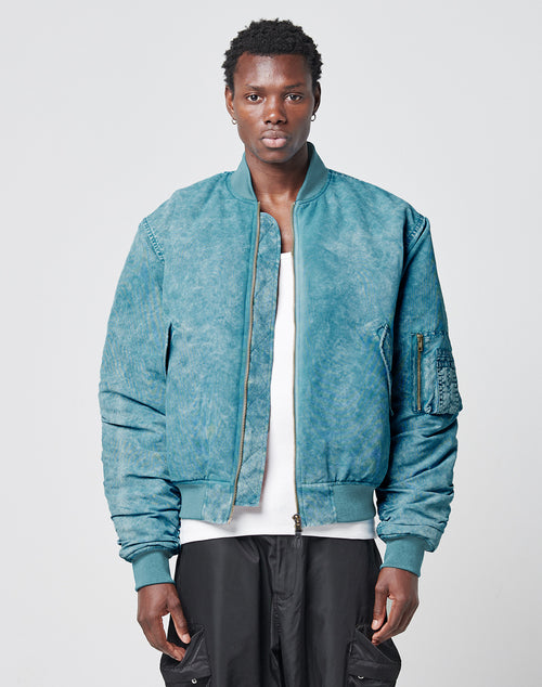 A man with short hair wears the LIVE FAST DIE YOUNG Washed Bomber Jacket over a white shirt and black pants, standing against a plain light gray background.