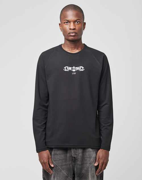 A person stands facing forward, wearing the LIVE FAST DIE YOUNG Live Fast Sports Longsleeve with white graphic text on the chest and faded black jeans, set against a plain gray background.