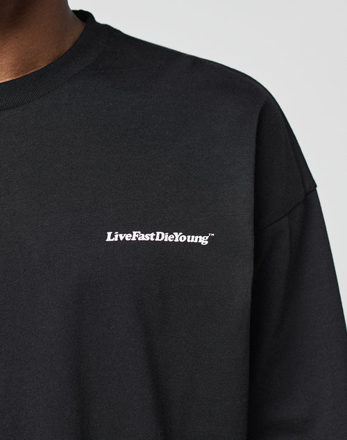 A person wears a black Basic Longsleeve by LIVE FAST DIE YOUNG, featuring a white LiveFastDieYoung™ logo print on the left chest; their face is not visible.
