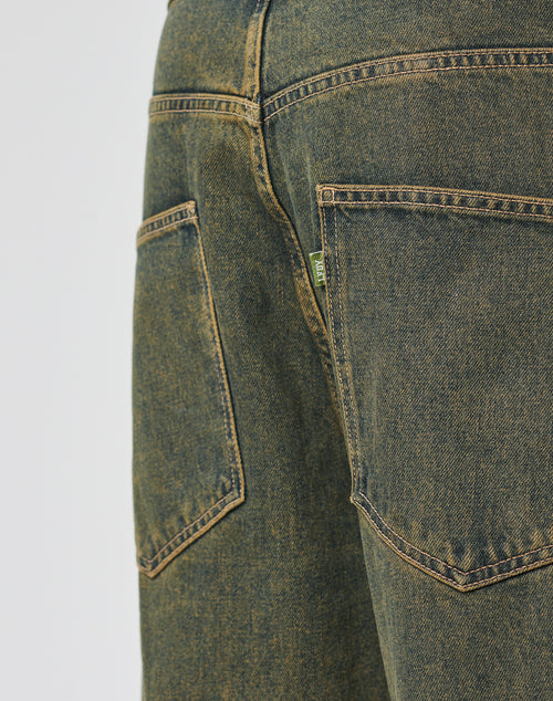 Close-up of the LFDY Baggy Denim by LIVE FAST DIE YOUNG in blue-green, featuring two large back pockets with yellow stitching, a small green tag, 100% Baumwolle material, a baggy fit, and a wide straight leg.