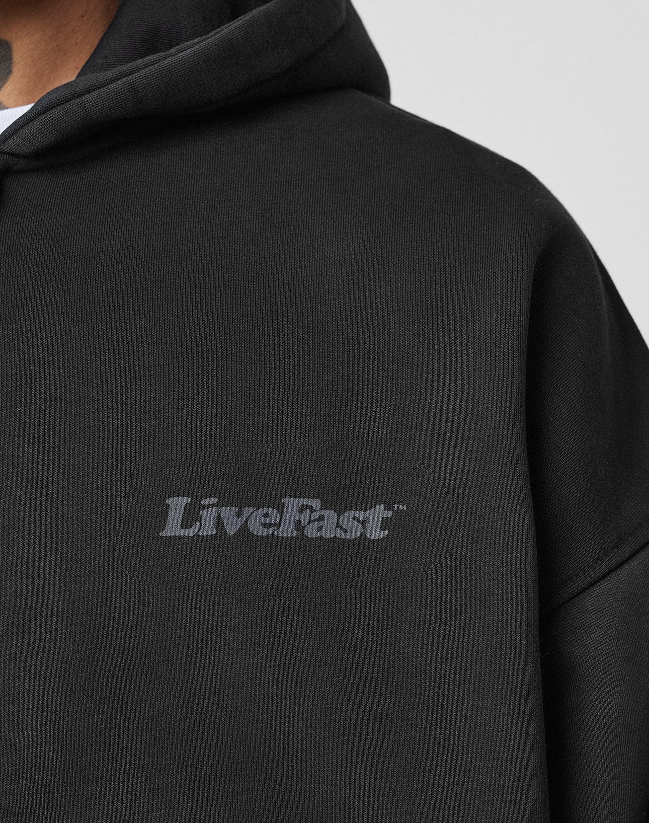 A close-up of a person wearing the LIVE FAST DIE YOUNG Basic 510 Hooded Zip in black. Only their neck and part of the chin are visible.