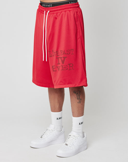A person wears LIVE FAST DIE YOUNG Live Fast IV Ever Shorts with an elastic waistband and side pockets, featuring LIVE FAST IV EVER print, white LFDY socks, white Nike Air Force 1s, and has a trumpet tattoo on their left shin.