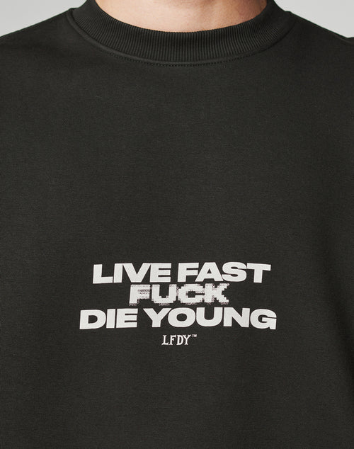 A close-up of the Fuck Die Young Sweater by LIVE FAST DIE YOUNG, an oversized black sweatshirt in soft cotton and polyester, featuring bold white LIVE FAST FUCK DIE YOUNG LFDFY text with a slightly pixelated FUCK on the front.