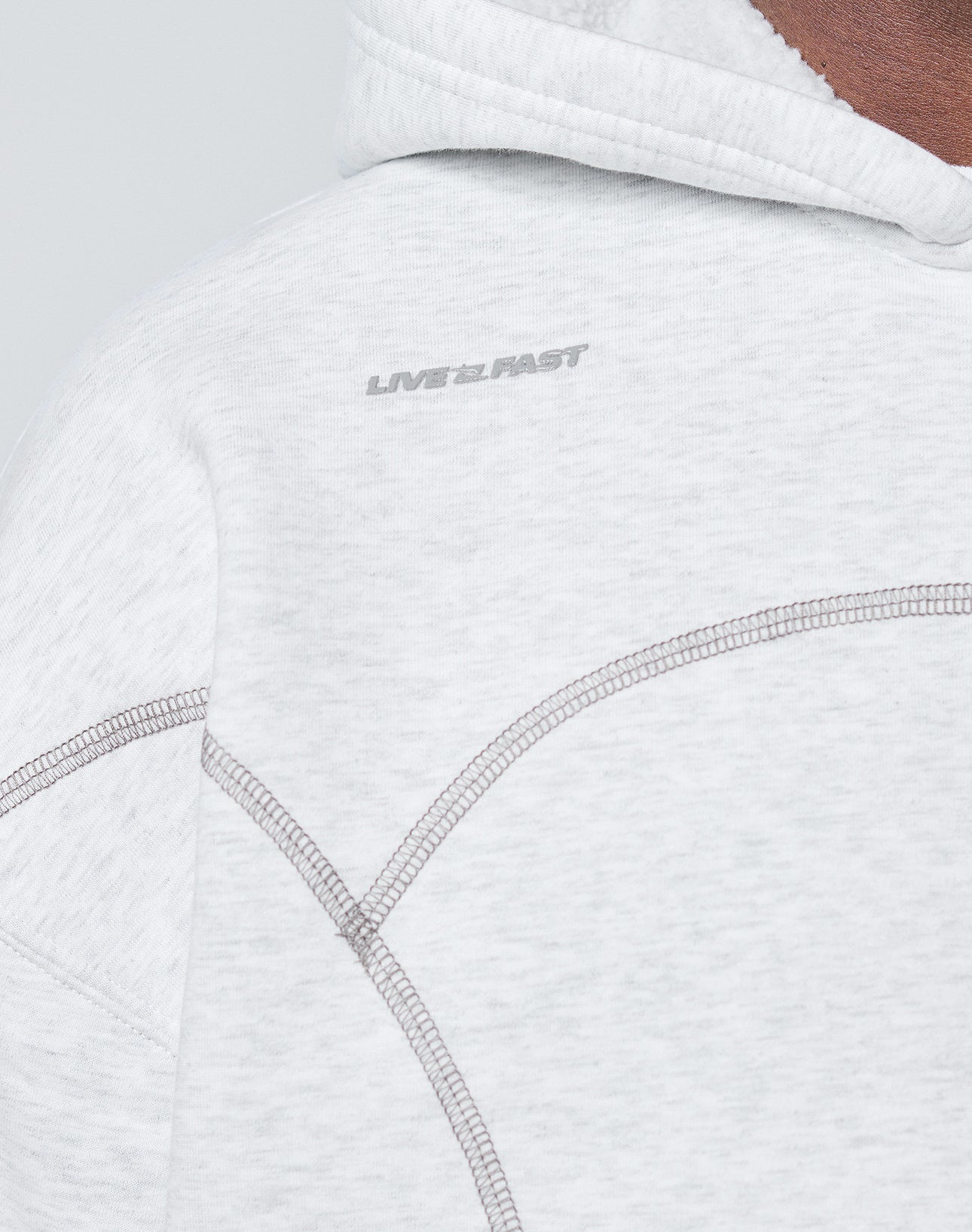 Close-up of the LFDY Active Fleece Hooded Zip by LIVE FAST DIE YOUNG in light gray Oversize Fit, with visible stitching and a subtle LIVE 2 FAST logo near the shoulder.