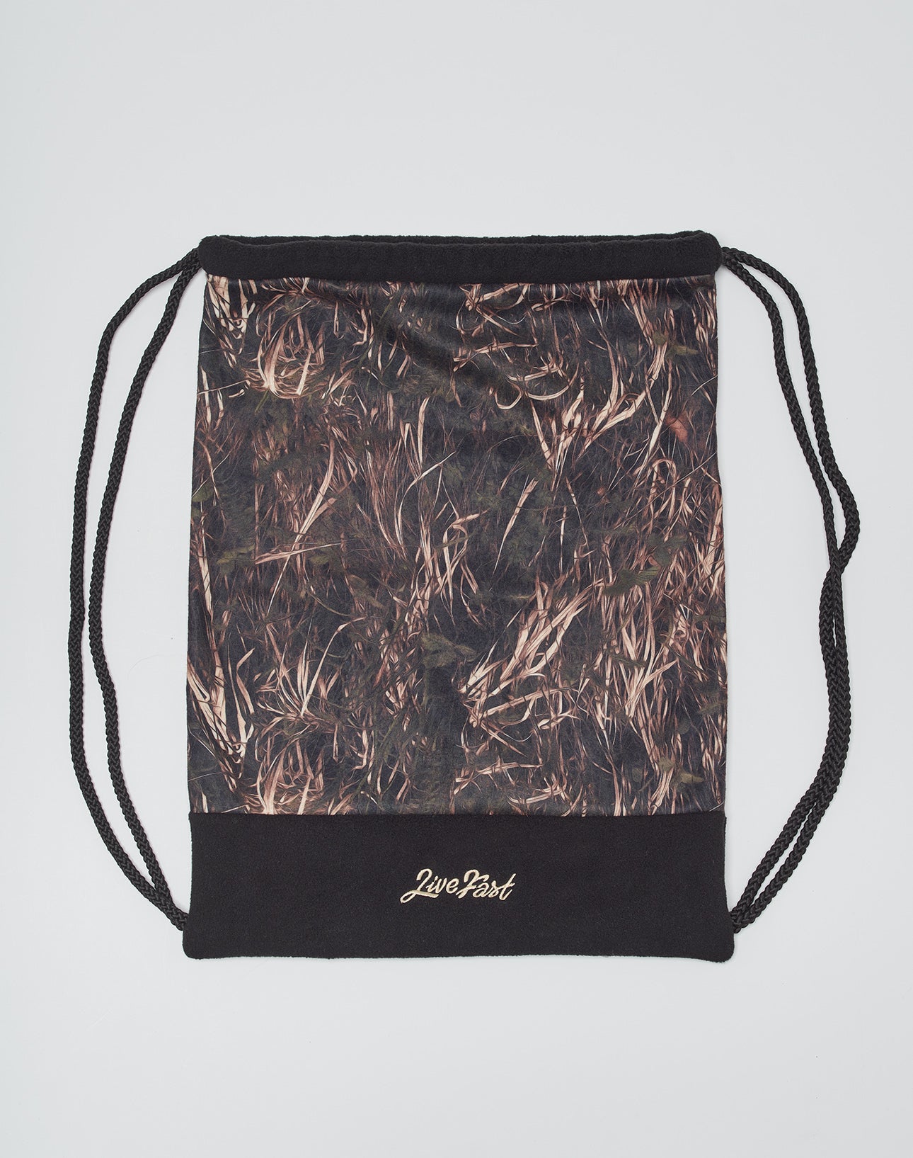 The Live Fast Gymbag by LIVE FAST DIE YOUNG is a polyester drawstring bag with black straps, brown and tan grass patterns, and Live Fast in gold lettering on a black panel—stylish for carrying your essentials.