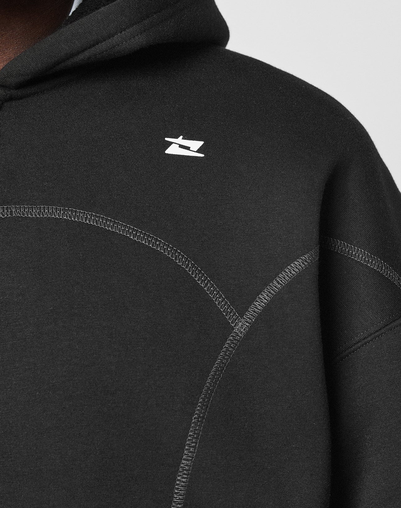 Close-up of the LFDY Active Fleece Hooded Zip by LIVE FAST DIE YOUNG in black, featuring an oversized fit, visible stitching, and a small white logo on the chest. The hood is up, showing part of the wearerās shoulder, neck, and jawline.