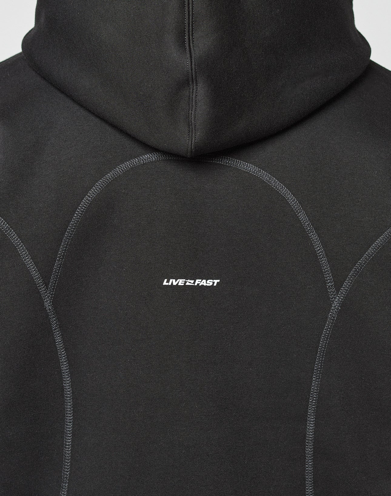 The back of the black LFDY Active Fleece Hooded Zip by LIVE FAST DIE YOUNG features an oversize fit, curved seams, a subtle logo, and LIVE FAST in small white letters at the center.