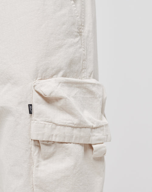 Close-up of a light beige cargo pocket on the Wide Summer Cargo pants by LIVE FAST DIE YOUNG, featuring a small black tag with white text. Made from soft, textured 100% Baumwolle Ripstop Stoff for comfort and durability.