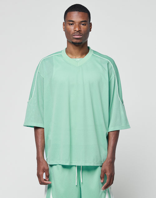 A man wearing the LIVE FAST DIE YOUNG Basic Mesh Jersey and matching mint green shorts with contrast piping stands against a white background, looking directly at the camera with a neutral expression.