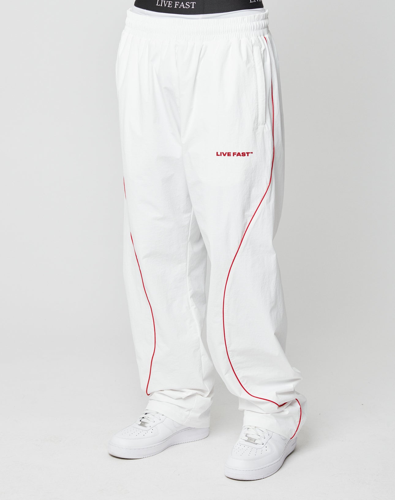 Someone wearing LIVE FAST DIE YOUNGs LFDY Wavy Trackpants in white wide fit.