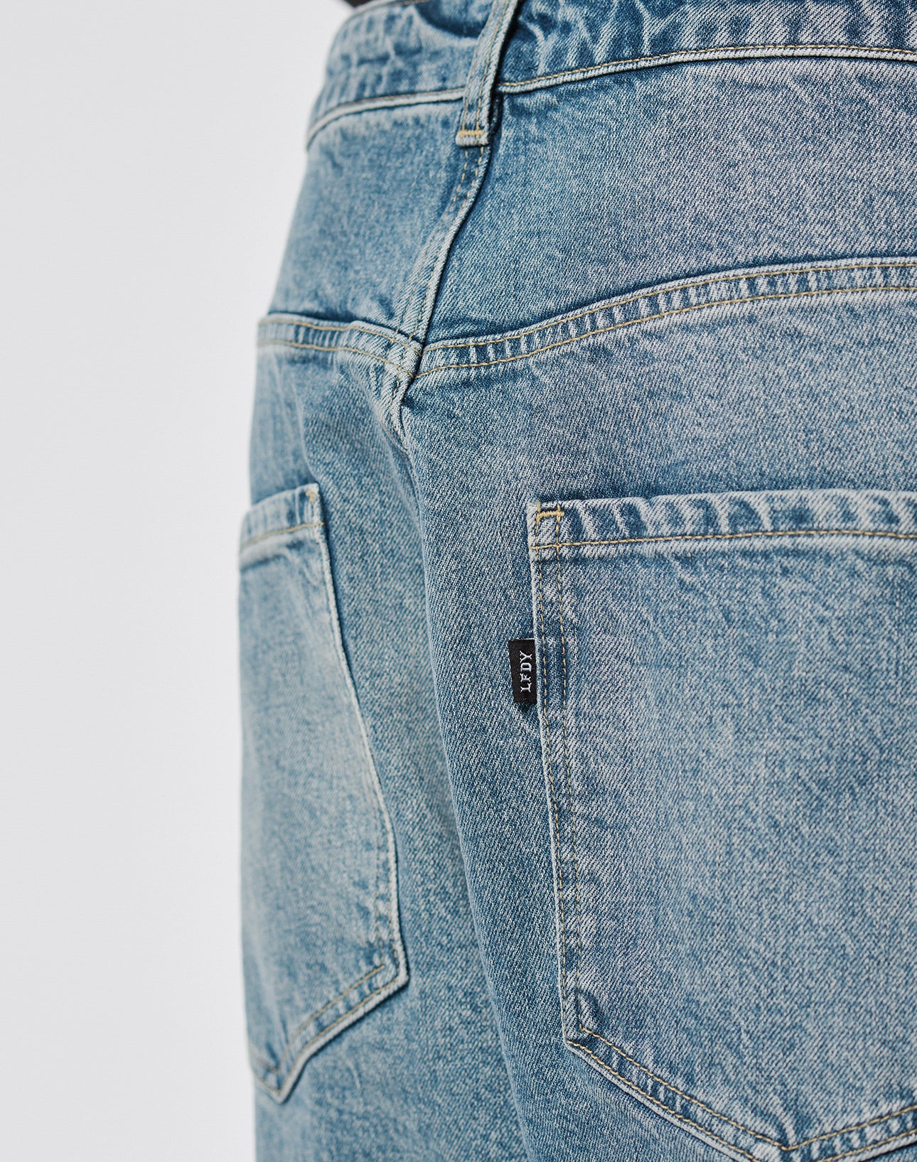 Close-up of the back of LIVE FAST DIE YOUNGs LFDY Tire Tracks Denim in a Baggy Fit, featuring two back pockets and a black label on the right pocket seam. Made from 100% Baumwolle for comfort and durability.